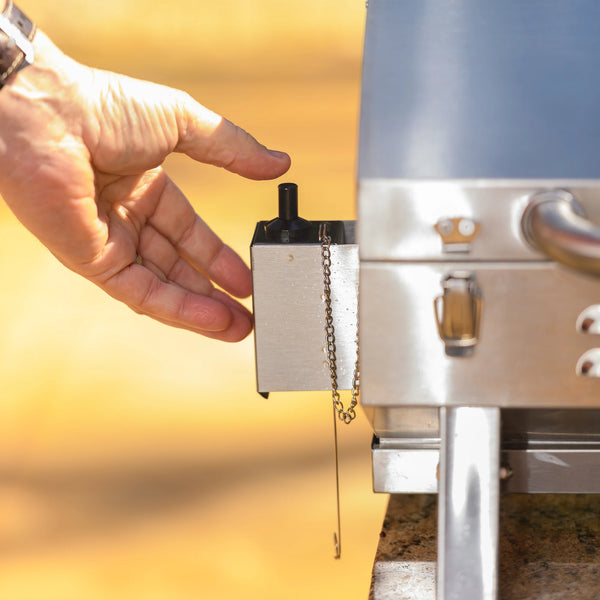 A person uses his thumb to push the ignitor button on the left side of the grill