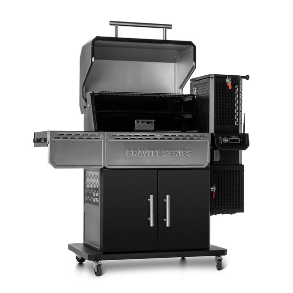 Gravity Series 1150 grill, open to show foldaway warming rack. Front shelves are down. Grill tilted to show utensil hooks on edge of side shelf and the vented wall of the enclosed cart.