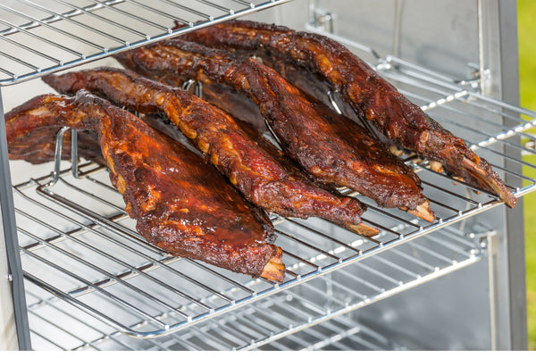 4 racks of ribs resting vertically in the rack with the rack placed on the cooking rack of a vertical smoker