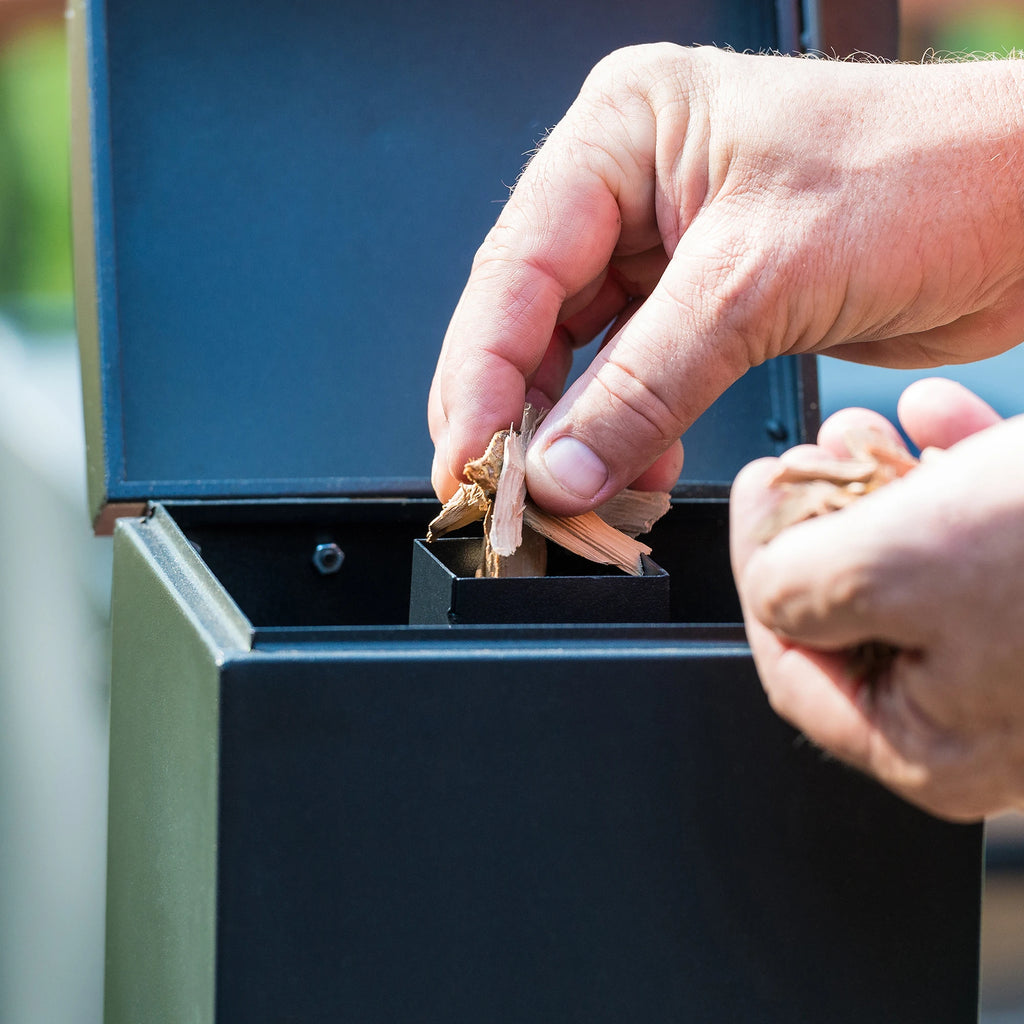 Loading wood chips into the slow smoker